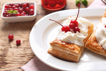 Tasty puff pastry dessert with berries and whipped cream on plate