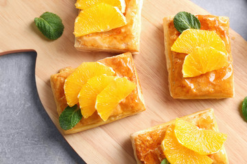 Fototapeta na wymiar Tasty puff pastry dessert with orange and mint on wooden board