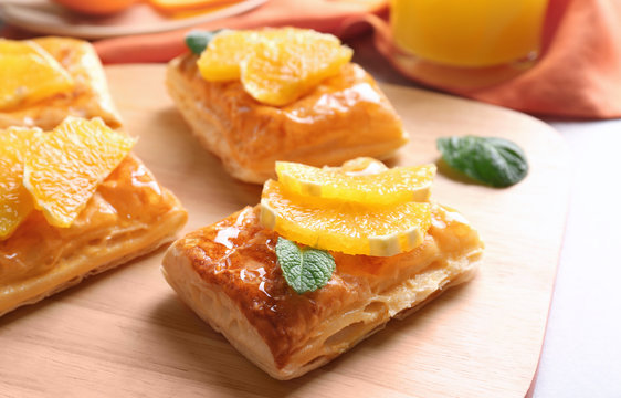 Tasty puff pastry dessert with orange and mint on wooden board