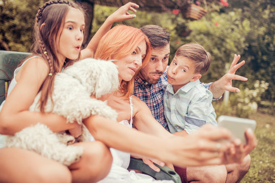 Happy family with dog taking selfie by smart phone in the park