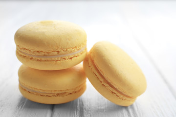 Tasty lemon macarons on white wooden table, closeup