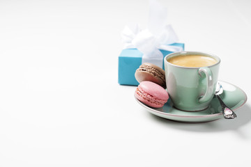 Cup of coffee and macarons on white background, copyspace