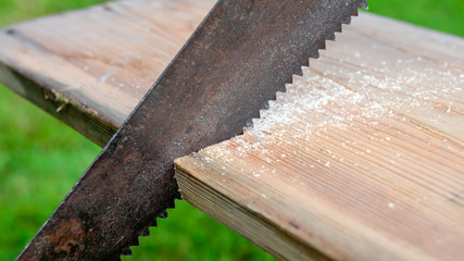 An old saw cuts a wooden board