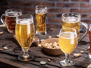 Glasses of beer and snacks on the wooden table.