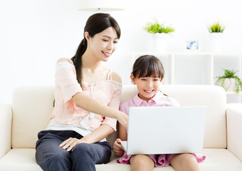mother with  daughter looking at Laptop  on sofa