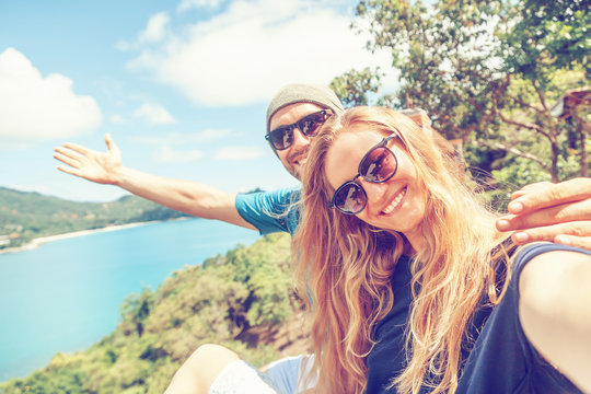 Young happy couple doing selfie on mobile phone overlooking beautiful tropical landscape