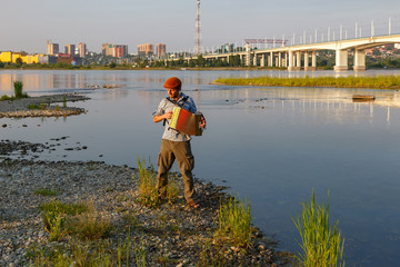 Man playing accordion at river side