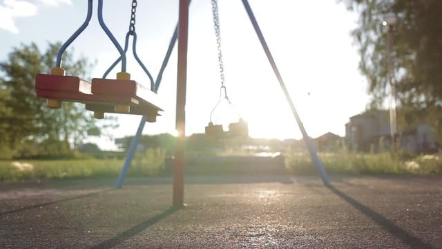 Children swing swaying in a summer park at sunset. no people