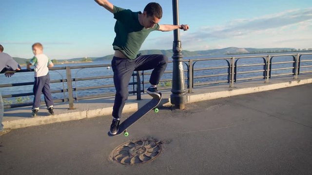 Young skater riding on his skateboard on the bank of the river.