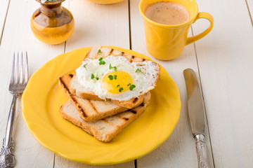Toast with egg in yellow plate near vase with flower on white wooden background. Healthy breakfast.