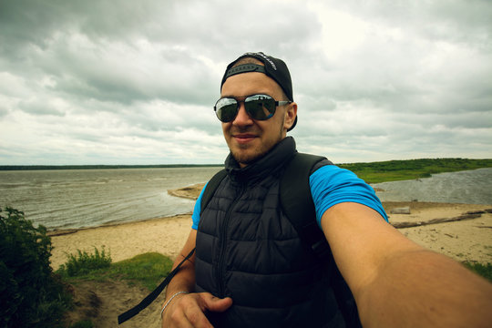 Man takes pictures of himself on the background of the river