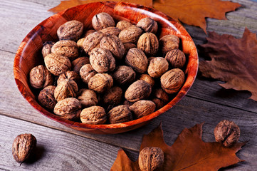 Walnuts amidst autumn leaves on a wooden table