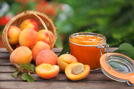 Wicker basket full of ripe apricots and apricot jam in a jar. Healthy diet food.