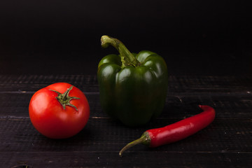 Fresh peppers and tomato on black background