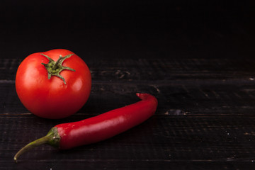 Fresh peppers and tomato on black background