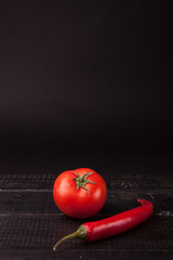 Fresh peppers and tomato on black background