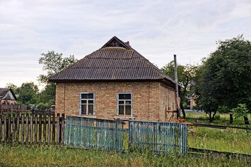 старый кирпичный сельский дом за деревянным забором в траве