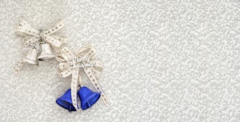 christmas card composition of two bells with ribbon bows, silver and blue, with copy space for your text at the side. new year and xmas conceptual background.