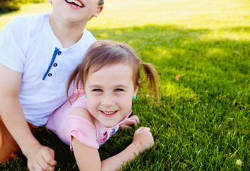 Happy little girl lying on grass with her brother