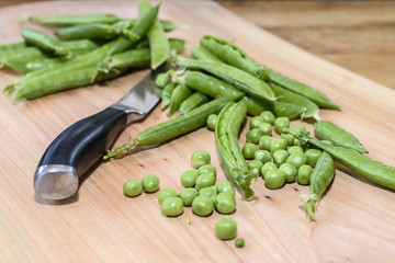 Pea and knife on a wooden board
