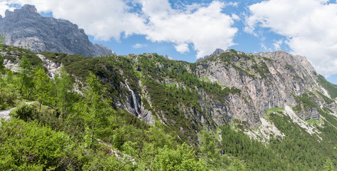 Fototapeta premium Waterfall at the foot of the mountain hut, Dolomites, Italy