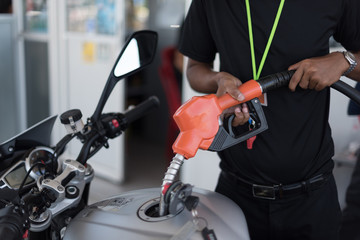 Obraz premium Gas station employee are fueling modern motorbikes in selective focus.