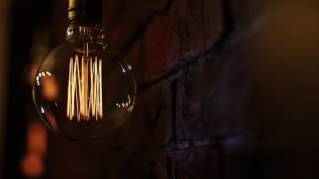 Edison bulb lights up and flickers on the brick wall background  
