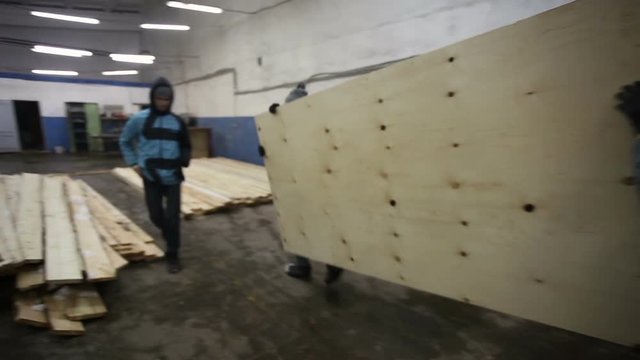 Two guys bring the plywood into the room