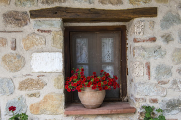 Fototapeta na wymiar Pot with flowers on typical window in Greece