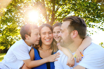 Fototapeta premium Joyful family sitting together embraced in summer