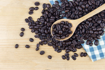 Top view of coffee bean on wooden spoon and plaid white and blue