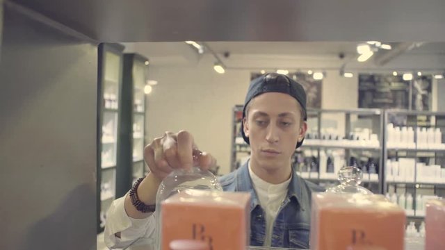 Young Man Choosing Candle In A Beauty Store