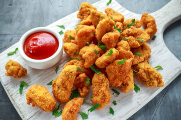 Fried crispy chicken nuggets with ketchup on white board