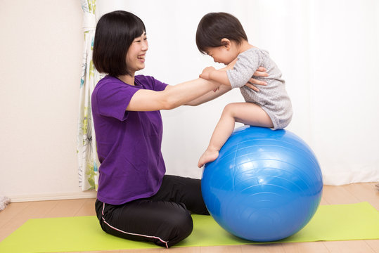 バランスボールに乗る子と支える母親