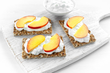 Homemade Crispbread toast with Cottage Cheese and nectarine on white wooden board.