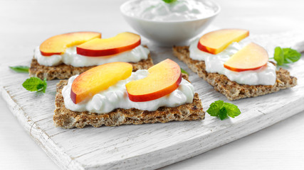 Homemade Crispbread toast with Cottage Cheese and nectarine on white wooden board.