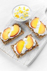 Homemade Crispbread toast with Cottage Cheese and nectarine on white wooden board.