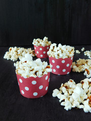 Popcorn in colourful red paper cups on a black background