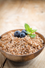 Buckwheat porridge in a bowl with mint leaves and blueberries.