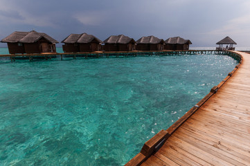 Tropical Maldives island resort with luxury water villas and wooden bridge
