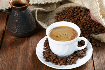 Cup with coffee on the table next to coffee beans