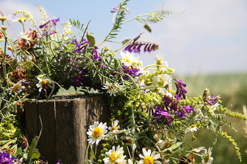 wreath of flowers hanging on a wooden stick on a wild field
