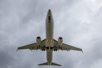 Fototapeta na wymiar Overhead view of passenger airplane short before landing. Overcast, cloudy sky.