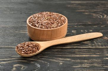 Flax seeds in spoon and bowl on a dark table
