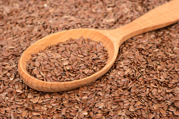 Wooden spoon in a scattered flax seeds close-up