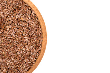 Part of a wooden bowl with flax seeds on white background, top view