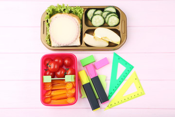 School lunch in boxes on pink wooden table