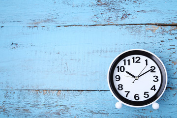 Black clock on blue wooden table
