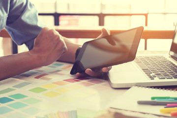 Color samples, colour chart, swatch sample, Graphic designer being selecting Color table and graphics tablet, pen at workplace with work example in camera and laptop on wooden desk