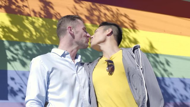 Couple kissing in front of rainbow flag